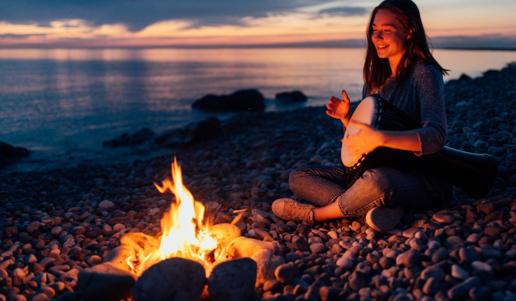 cheerful girul watching at bonfire with rocks