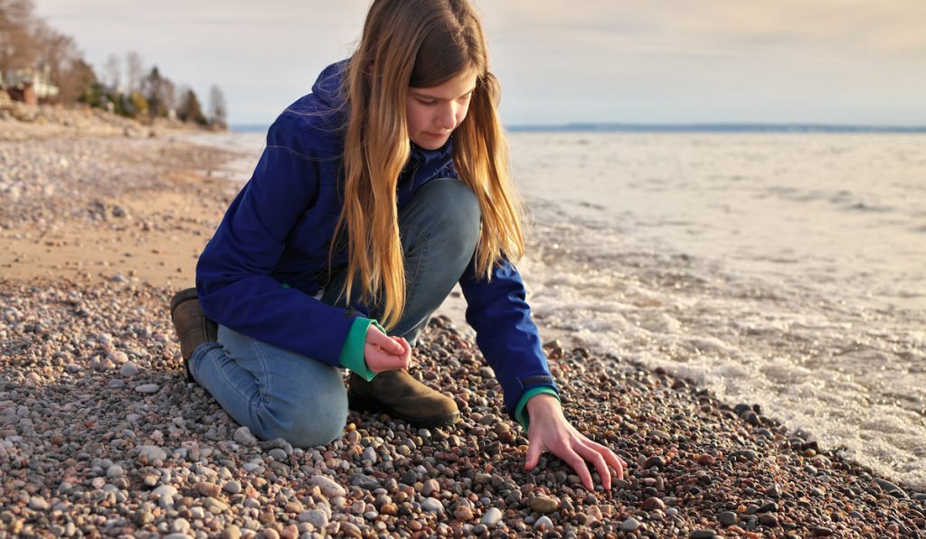 girl collecting rocks at the beach